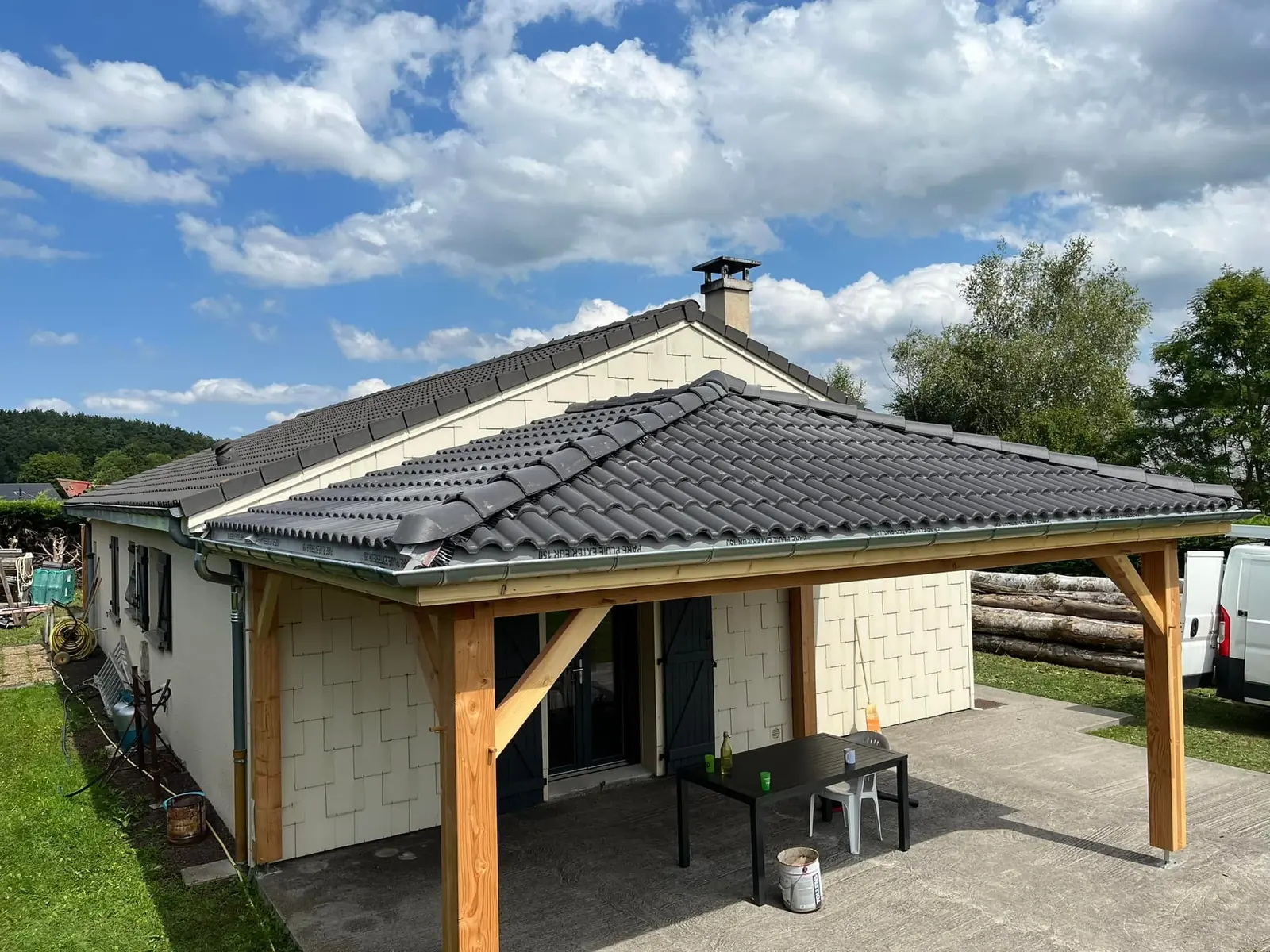 Auvent en bois couvert de tuiles, accolé à une maison de plain-pied