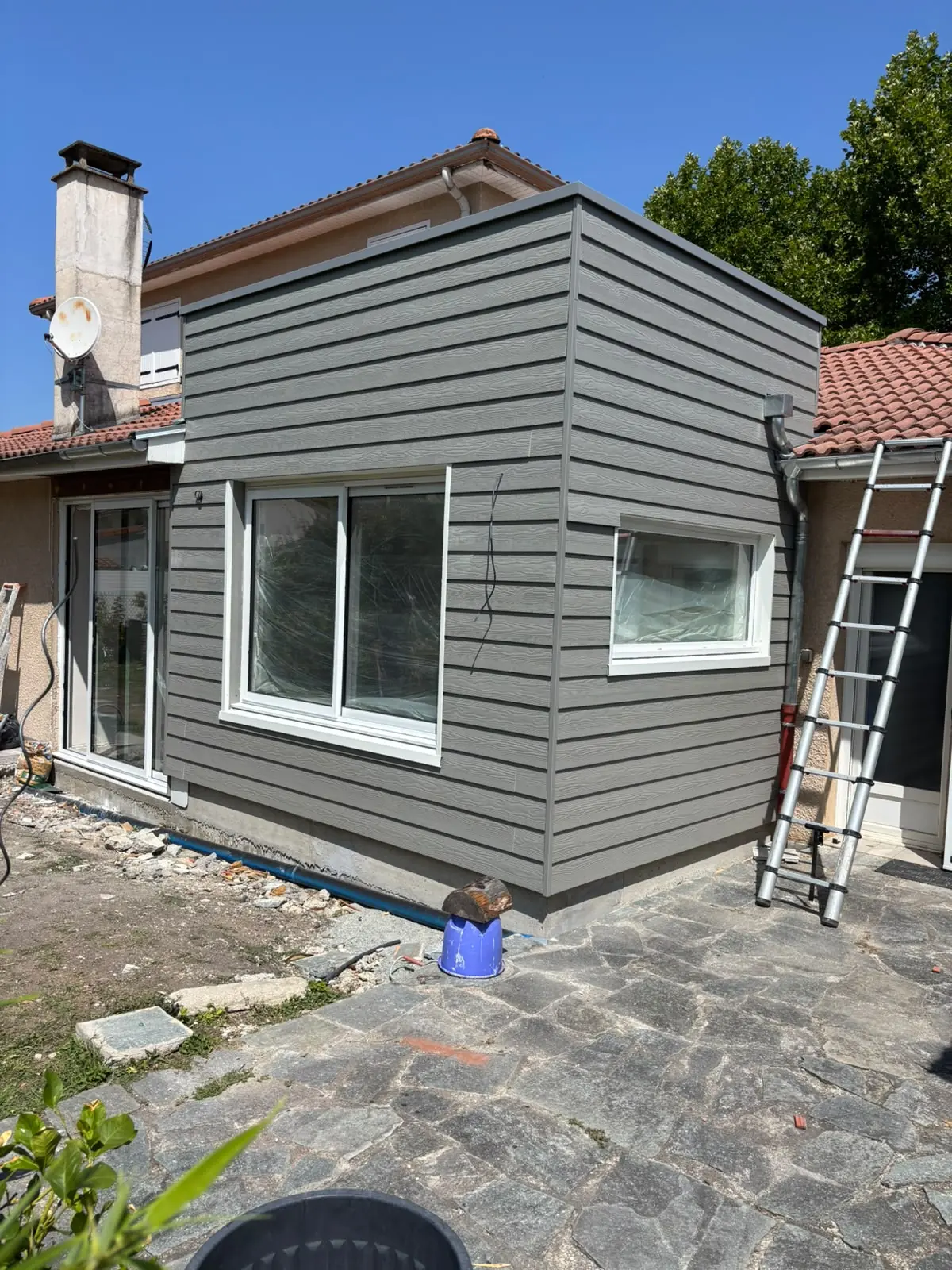 Extension terminée en bardage gris, fenêtres posées