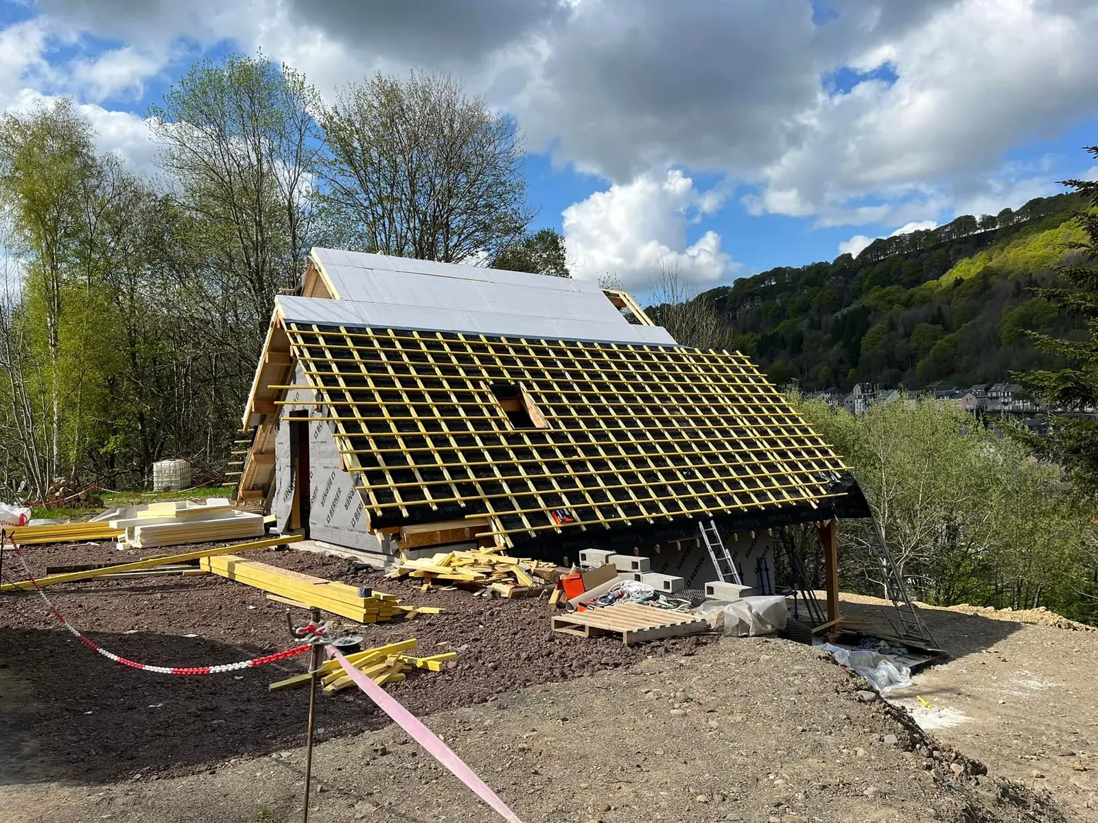 Toiture en cours de pose, liteaux et écran sous toiture, devant une colline boisée