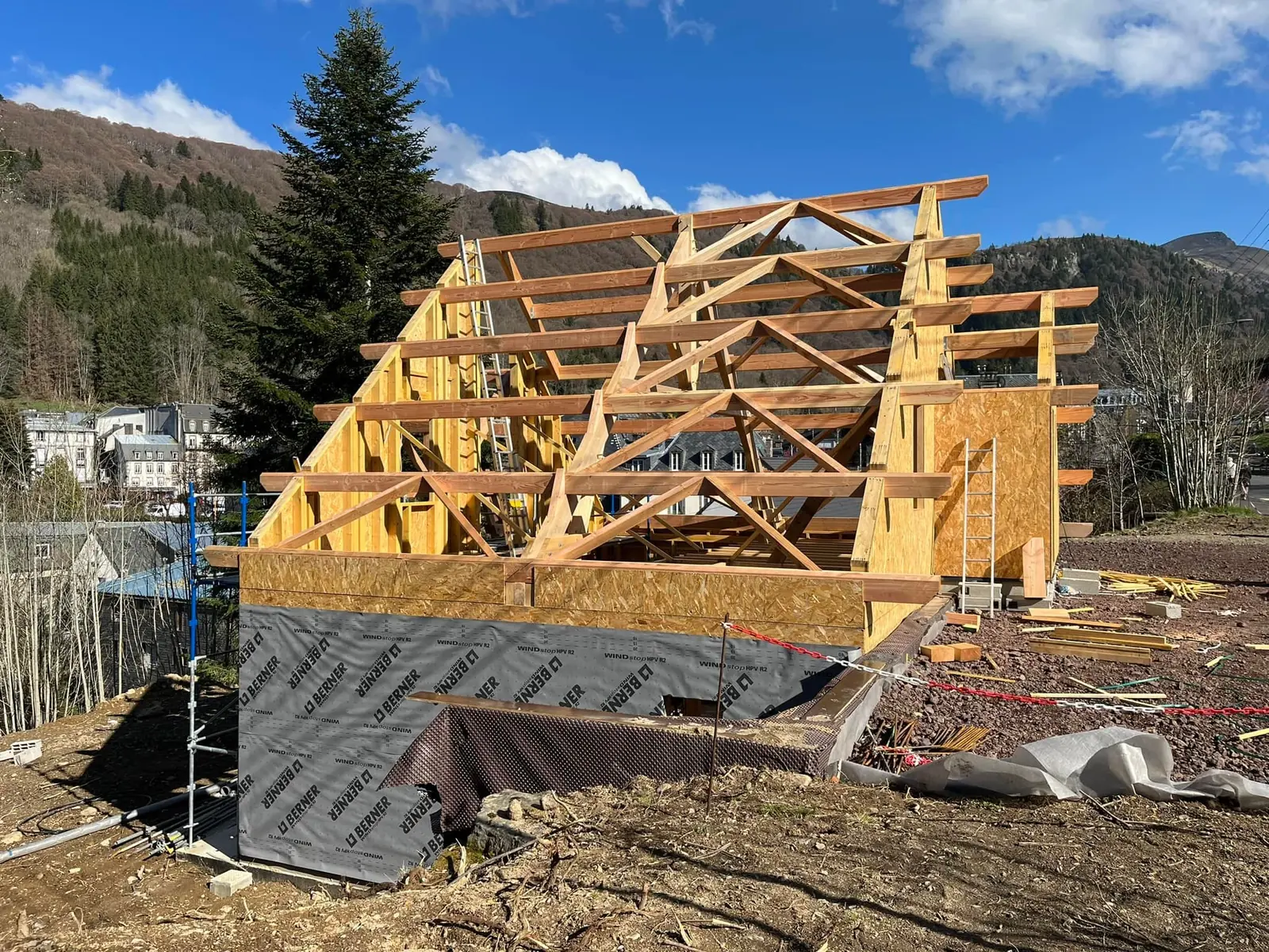 Charpente neuve en bois levée sur une maison en construction, au pied des montagnes