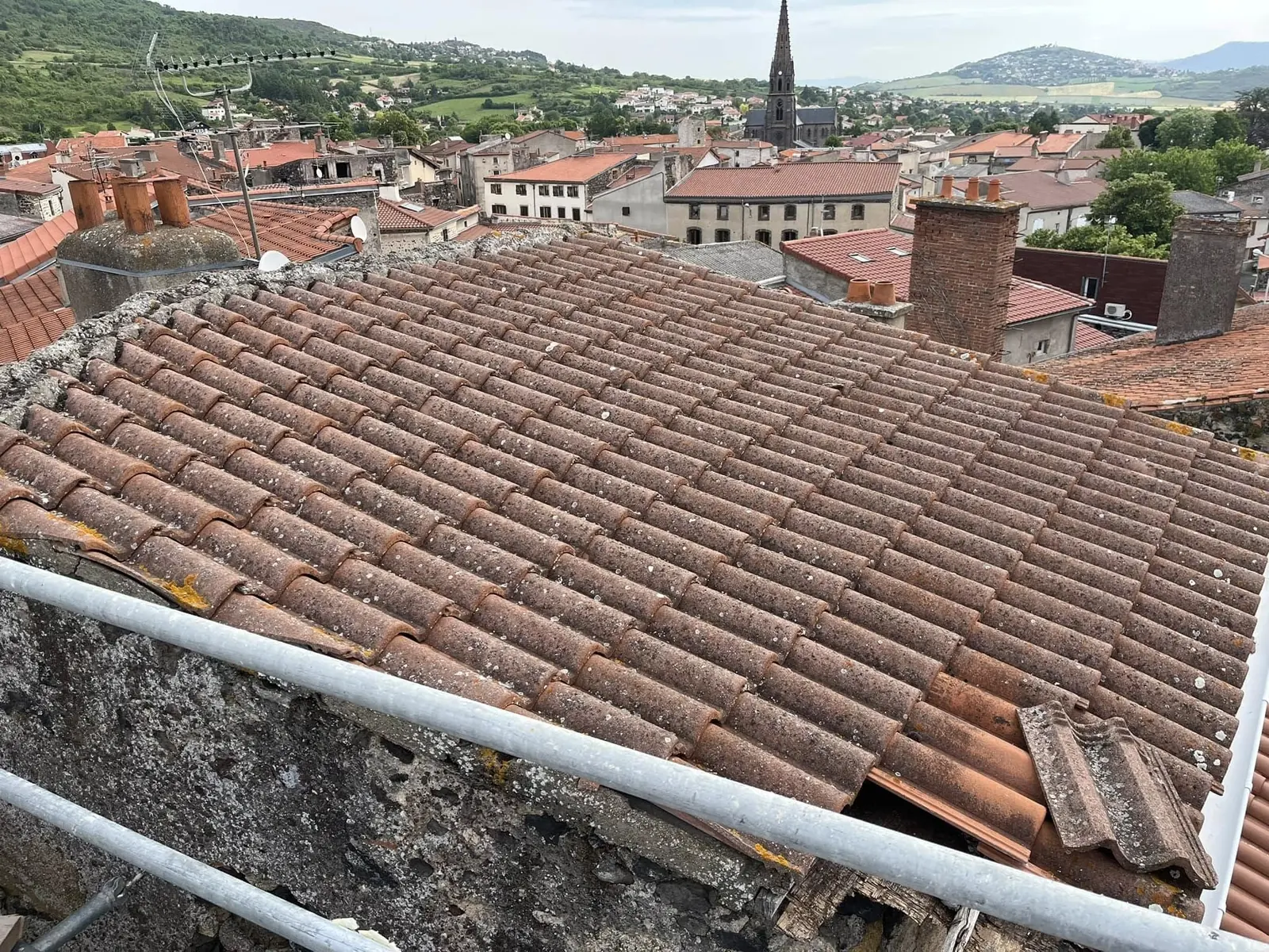 Toiture en tuiles en cours de rénovation, garde-corps de chantier posé en bas de pente